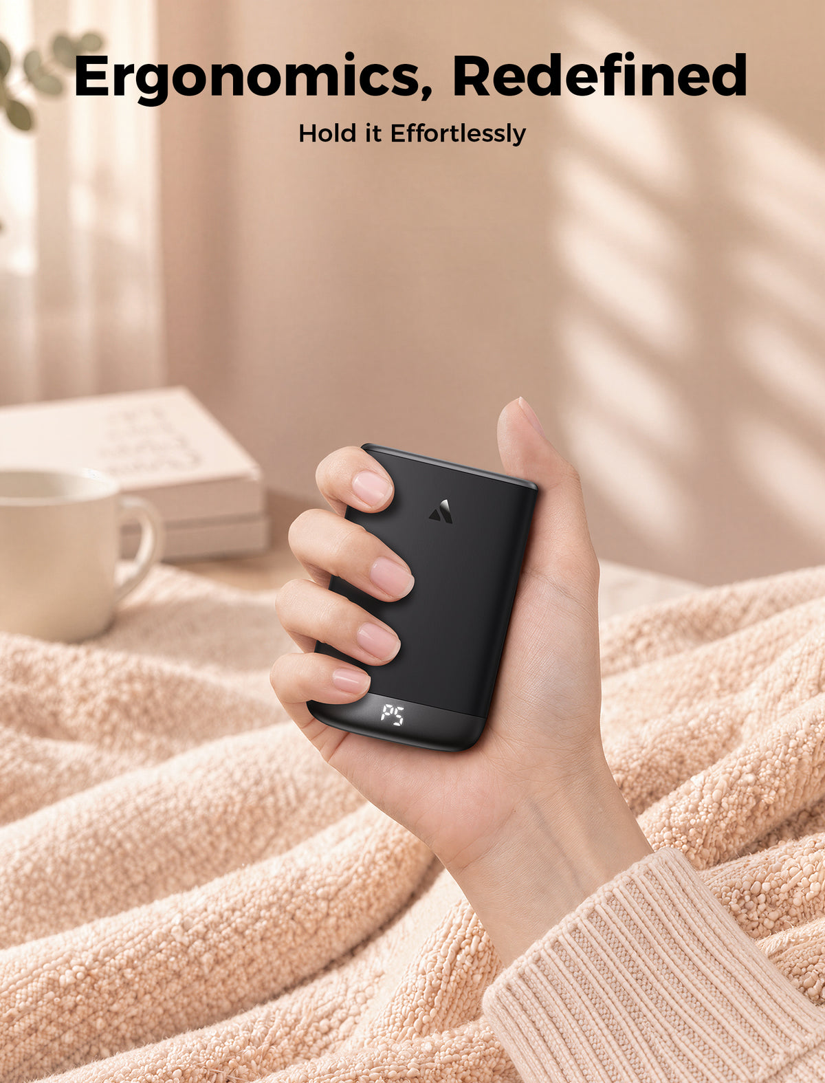 Gray Glow Air hand warmer held comfortably in the palm on a soft blanket at home

