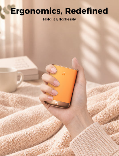 Orange Glow Air hand warmer held comfortably in the palm on a soft blanket at home
